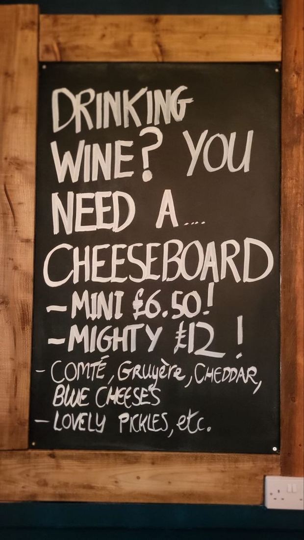 The pub's chalkboard: Drinking wine? You need a… cheeseboard. Mini! Mighty! Comté, Gruyère, Cheddar, blue cheeses. Lovely pickles, etc.